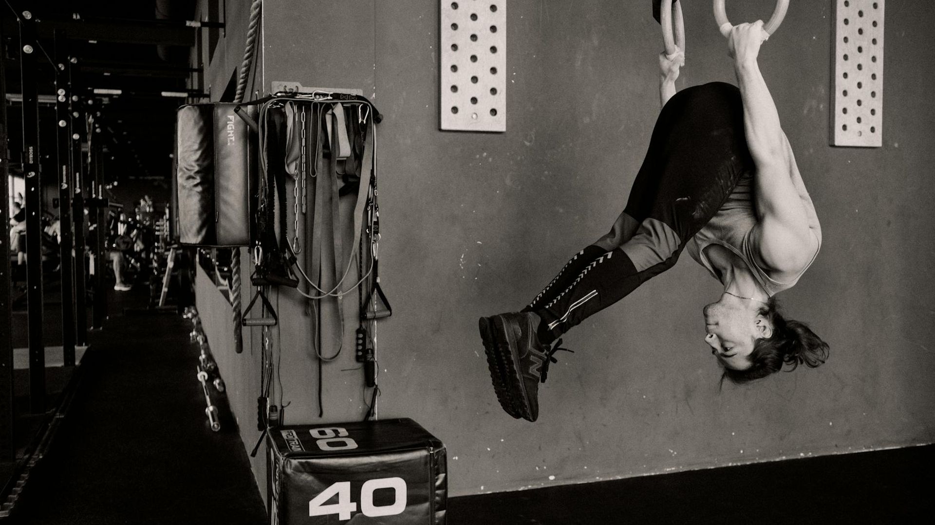 Athletic man performing strength exercises in a dark modern gym environment.