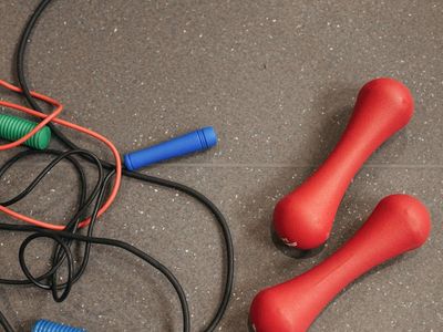 Close up of steel dumbbells on a dark rubber gym floor.